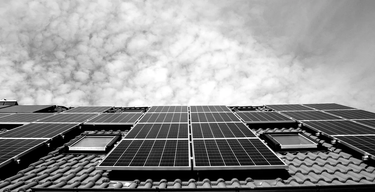 Panneaux solaires installés sur un toit de tuiles sous un ciel nuageux