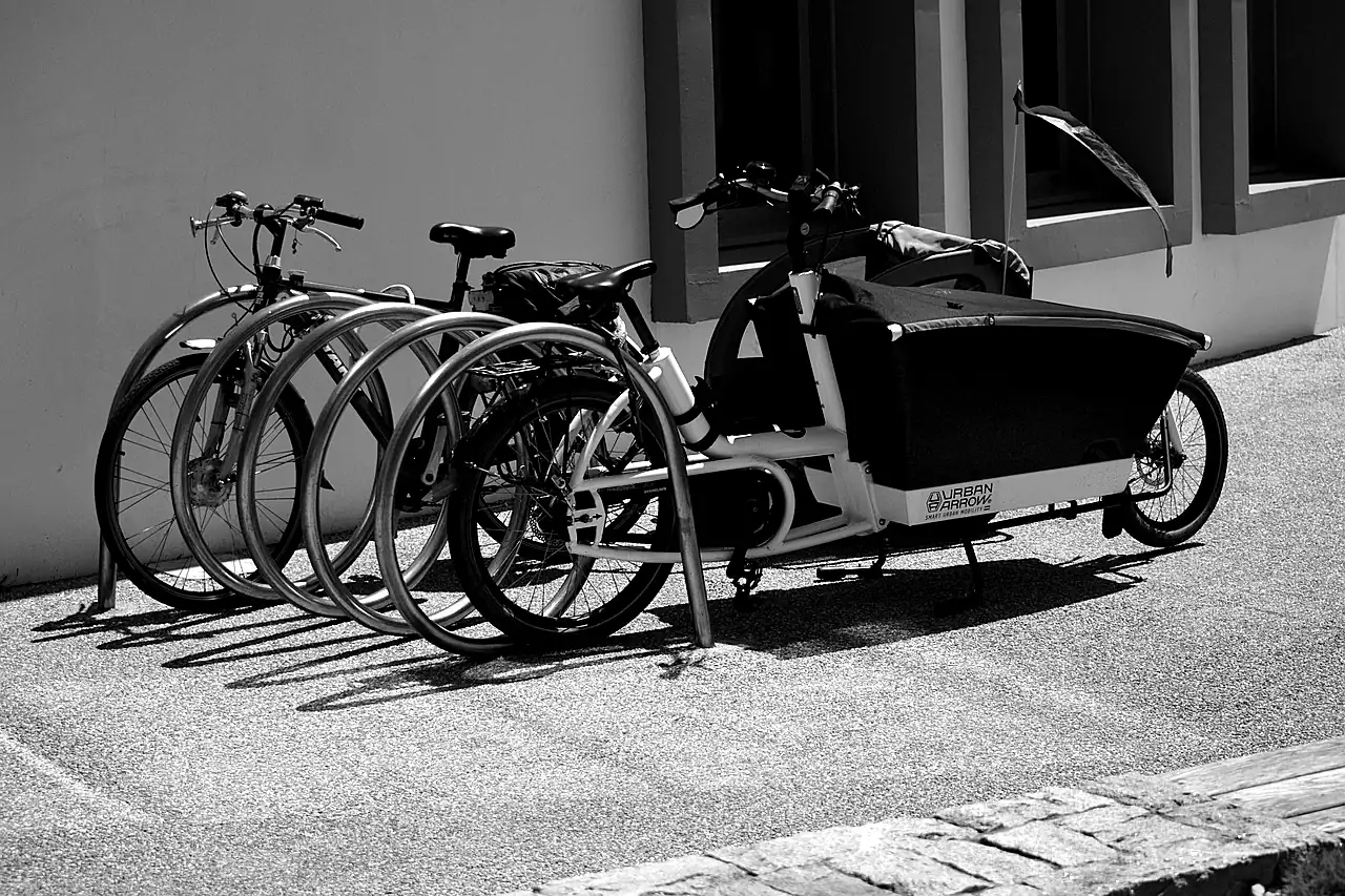 Vélos et vélo-cargo stationnés contre un mur, en noir et blanc